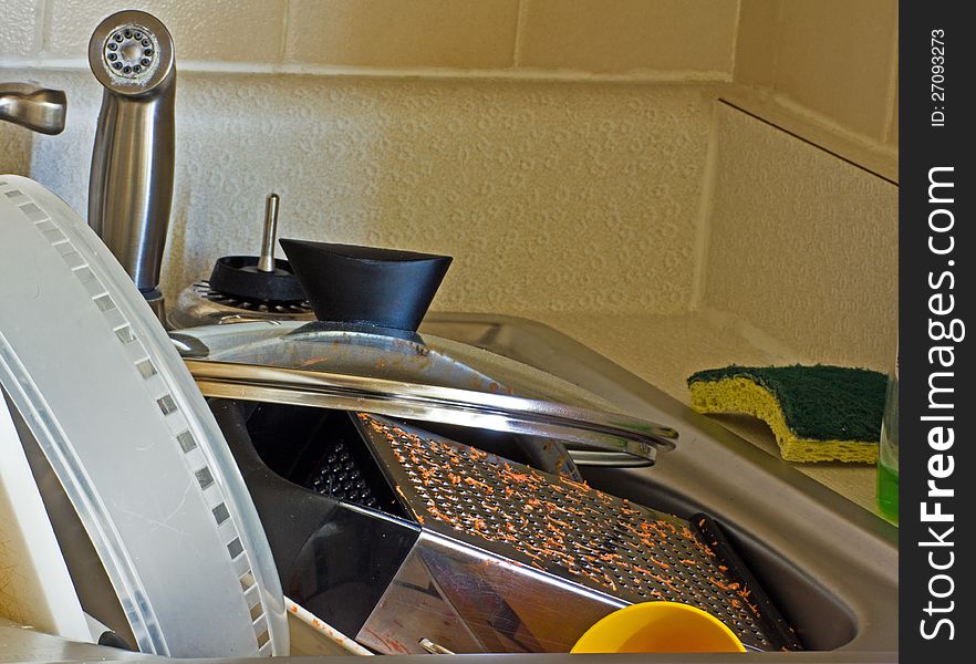 Sink full of dirty dishes and cookware.