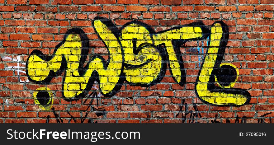 Yellow graffiti on red brick wall. Yellow graffiti on red brick wall