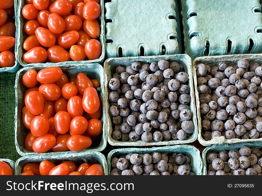 Small containers of baby tomato and blue berries for sale in the farmers market. Small containers of baby tomato and blue berries for sale in the farmers market