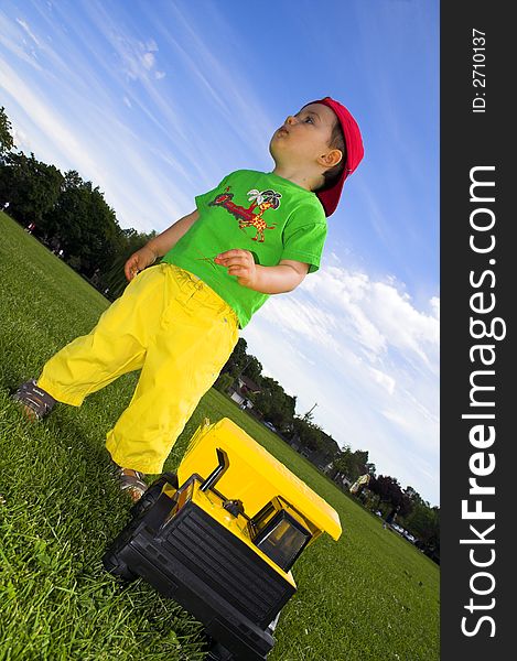 Child playing with truck outside over deep blue sky