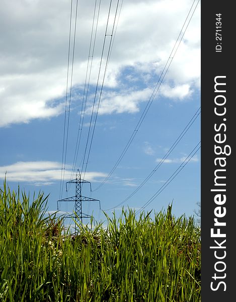 Taken from a low angle, electricity pylons seem to rise out of lush green grass. Taken from a low angle, electricity pylons seem to rise out of lush green grass.