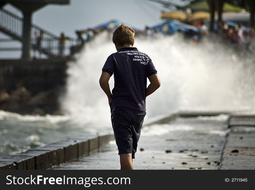 Boy walking on seacoast with splashes. Boy walking on seacoast with splashes