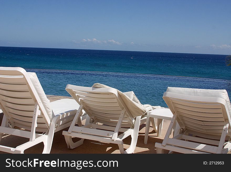 Chairs next to the pool watching the sea at Los Cabos, Baja California, Mexico, Latin America. Chairs next to the pool watching the sea at Los Cabos, Baja California, Mexico, Latin America