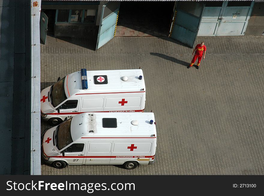 Two ambulance cars on a parking place and a hospital worker in red overall