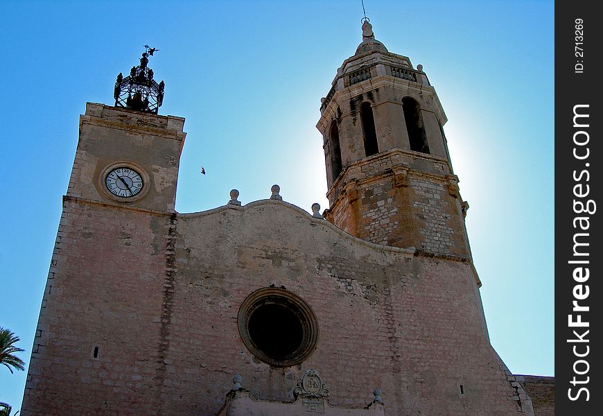 Sun casts glow behind tower of seaside church. Sun casts glow behind tower of seaside church