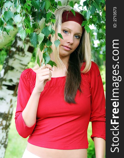 Outdoor beauty portrait of a young smiling woman in nature against a tree