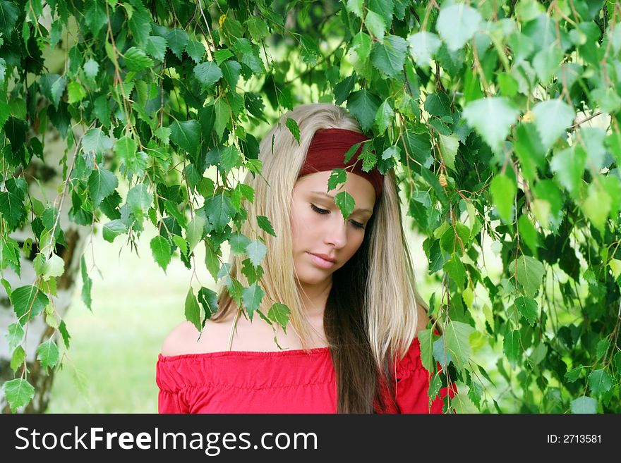 Outdoor beauty portrait of a young smiling woman in nature against a tree