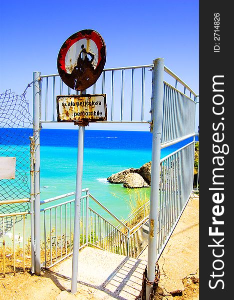 Rusty Italian beach sign with stairs leading to the water