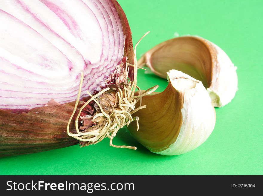 Red onion and garlic gloves on green background. Red onion and garlic gloves on green background