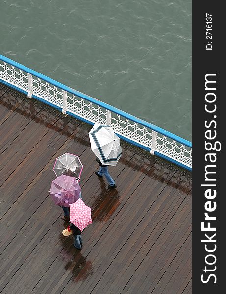 Family walk in the rain on a seaside pier