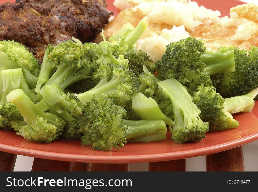Fresh steamed broccoli on an orange plate.