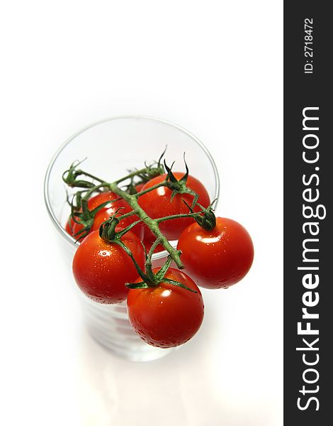 Vine of wet cherry tomatoes in a glass, soft focus.