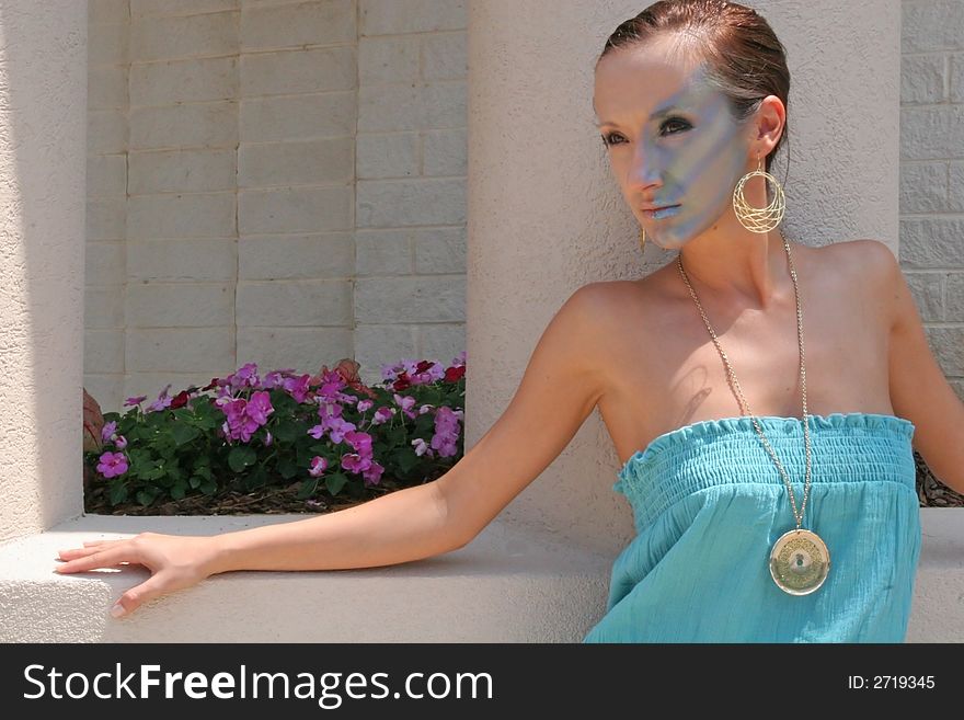 A fashion makeup model leaning against a planter. A fashion makeup model leaning against a planter