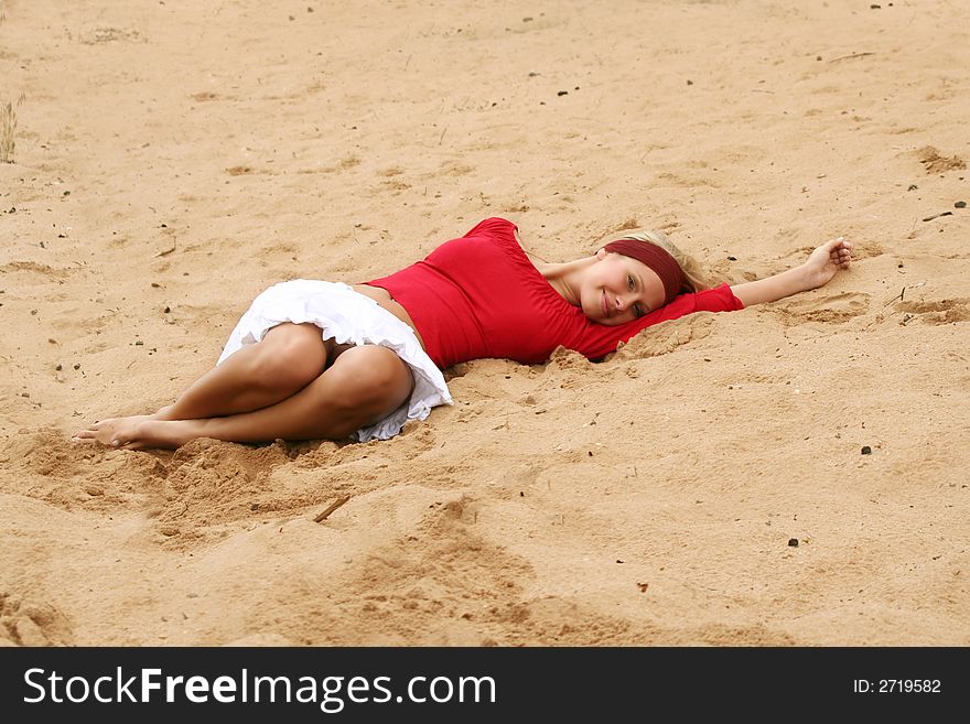 A young beautiful woman lying on a beach is smiling. A young beautiful woman lying on a beach is smiling