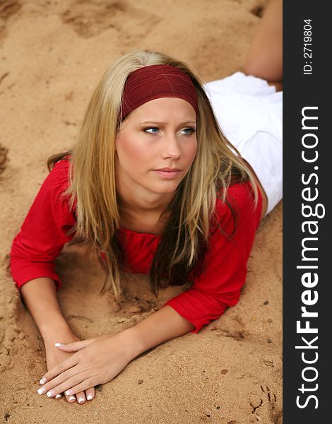 A young beautiful woman lying on a beach is smiling. A young beautiful woman lying on a beach is smiling