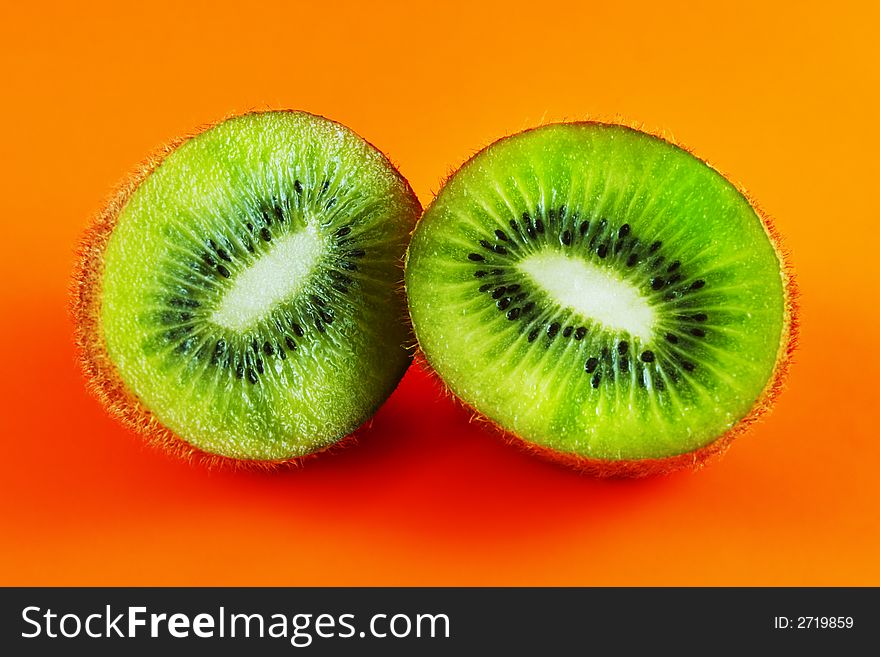 Sliced open kiwi macro shot on a orange background