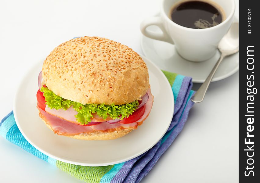 Roast Beef Sandwiches with Lettuce, Tomatoes and Red Onions on a white plate. Coffee on background