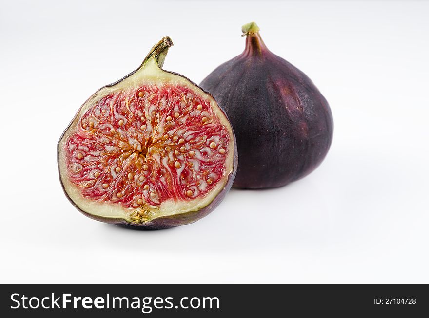 A shot of one fig and one half of fig on white , sharp details on seeds. A shot of one fig and one half of fig on white , sharp details on seeds