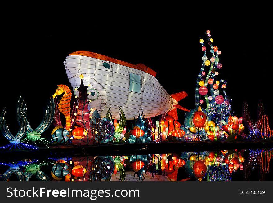 Colorful lanterns and their reflection in water, with colorful marine lives and submarine in shark shape.