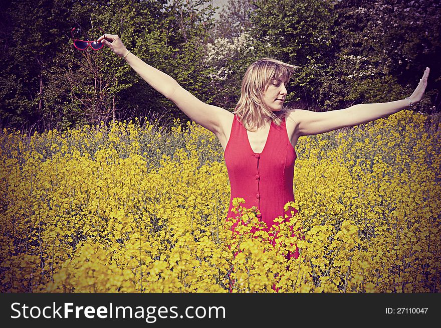 Girl in rapeseed field, dancing with joy. Vintage style