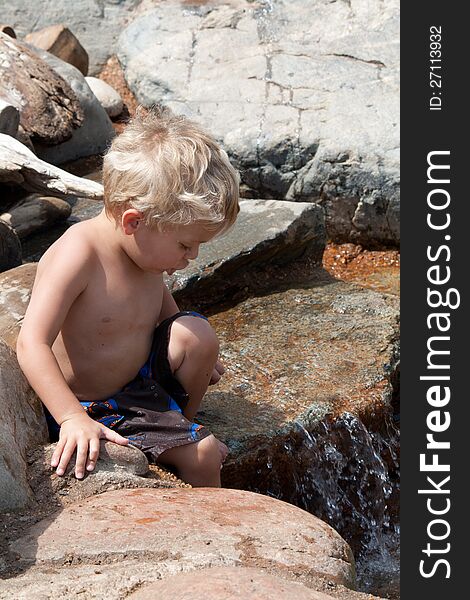 Small child wading and climbing in rocky stream. Small child wading and climbing in rocky stream.