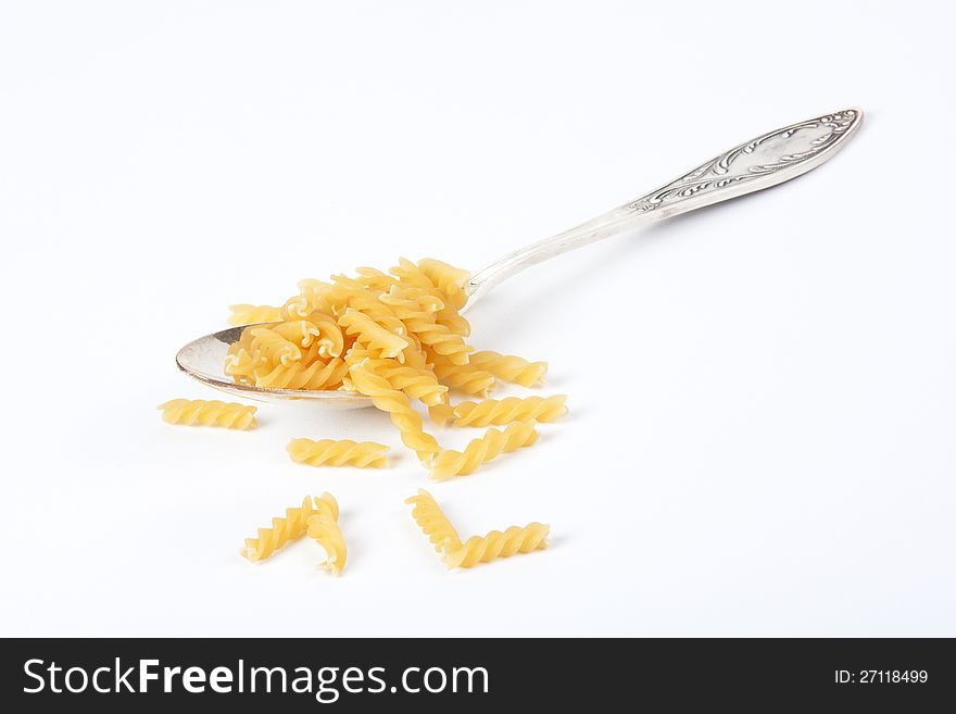 Uncooked pasta on a spoon isolated on white