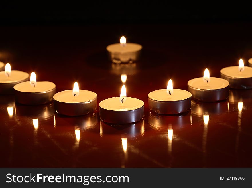 Set of lighting candles in a row on dark background. Set of lighting candles in a row on dark background