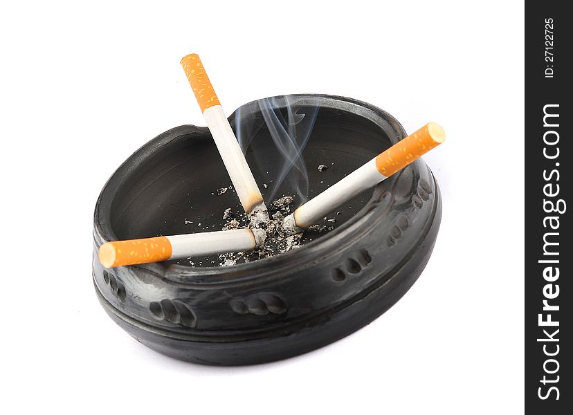 Three lit cigarettes in a black ashtray isolated on a white background