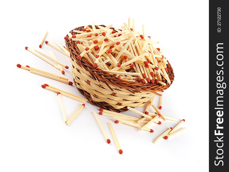 A pile of matches in a straw basked with some on the outside isolated on a white background. A pile of matches in a straw basked with some on the outside isolated on a white background