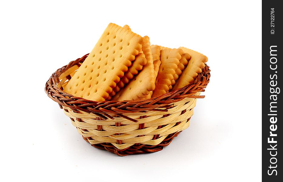 Pile of tea biscuits arranged in a straw basket isolated on a white background. Pile of tea biscuits arranged in a straw basket isolated on a white background