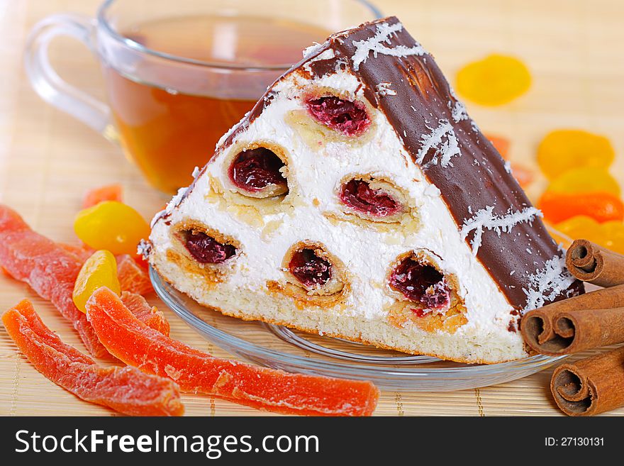 Piece of a pie with cherries, tea and candied fruits