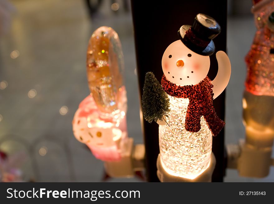 A smiling snow-woman night light with warm background.