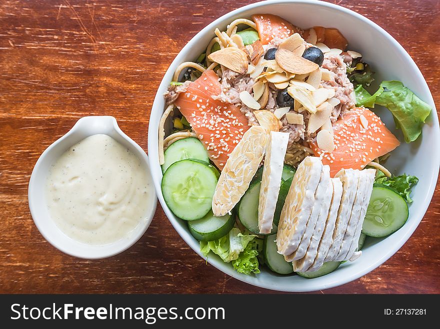 Salmon tuna fish salad with fresh green vegetable and cream sauce in white ceramic bowl. Salmon tuna fish salad with fresh green vegetable and cream sauce in white ceramic bowl
