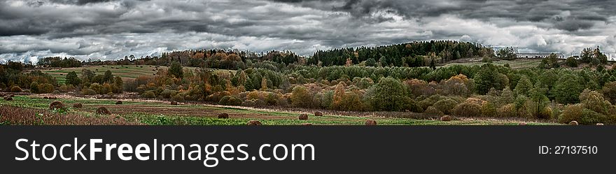 Panorama of rural landscape with yellow trees, straw bales and dramatic sky in autumn â€“ HDR image. Panorama of rural landscape with yellow trees, straw bales and dramatic sky in autumn â€“ HDR image