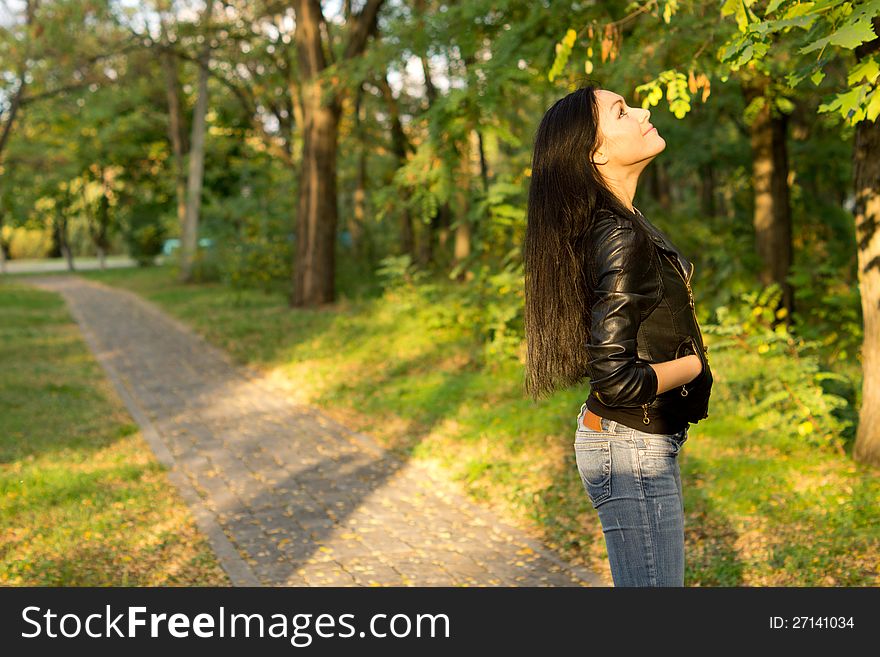 Young woman on a park path looking at trees. Young woman on a park path looking at trees.