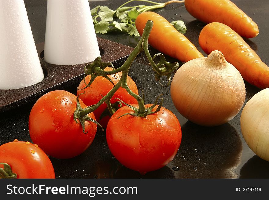 Bunch of red tomatoes with drops of water, surrounded by onion and carrots. Bunch of red tomatoes with drops of water, surrounded by onion and carrots