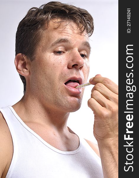 Sick man checks his temperature and holds thermometer under his own tongue