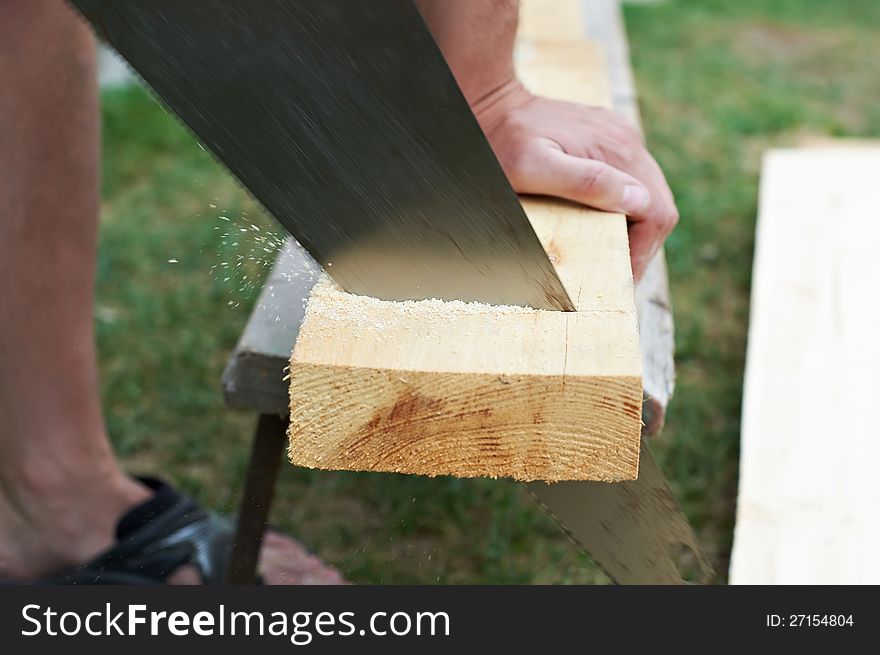 Man sawing a wooden board outdoors
