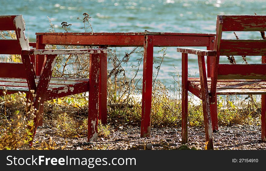 Shot a worn table and couple of chairs on a beach.