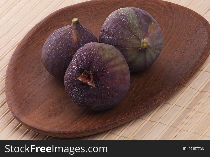 Three Perfect Ripe Figs Full Body with Droplets on Wooden Plate. Three Perfect Ripe Figs Full Body with Droplets on Wooden Plate