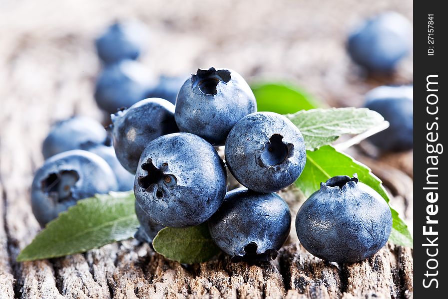 Blueberries with leaves on a old wooden table.