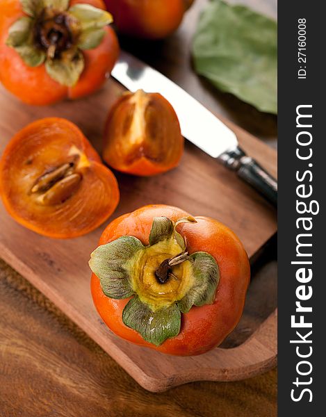 Ripe persimmon on a cutting wooden board