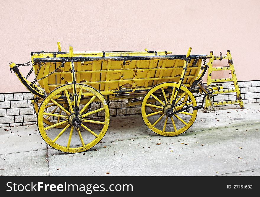 Old yellow wooden wagon standing in front of a wall of rose. Old yellow wooden wagon standing in front of a wall of rose