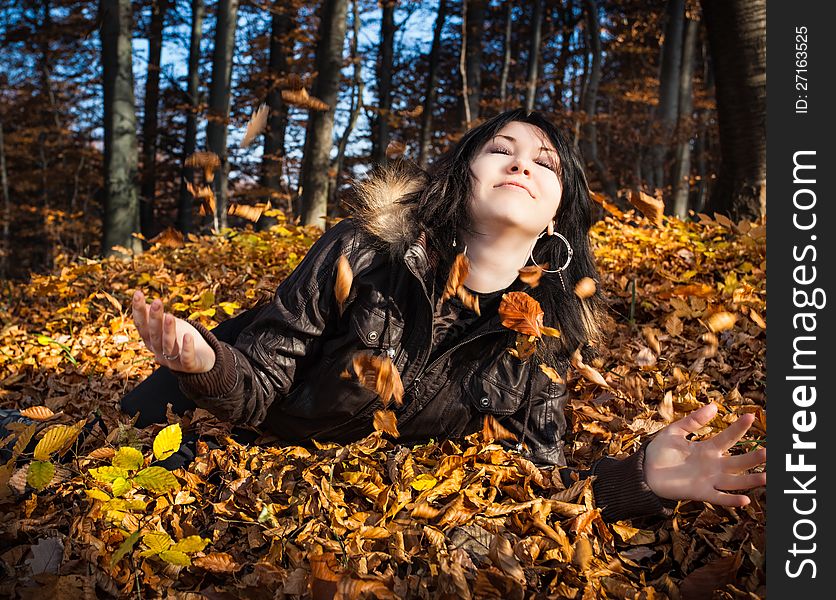 Young woman lying in fallen autumn leaves. Young woman lying in fallen autumn leaves