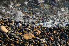 Crystal Clear Water On The Seashore. The Beach Is Lined With Small Colorful Pebbles. Sea Foam From The Waves. Royalty Free Stock Photo