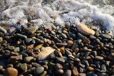 Sea Foam From Small Waves. Crystal Clear Water On The Seashore. The Beach Is Lined With Small Colorful Pebbles. Stock Photography