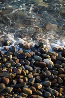Crystal Clear Water On The Seashore. The Beach Is Lined With Small Colorful Pebbles. Sea Foam From The Waves. Stock Photography