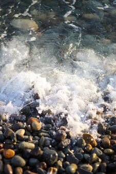 Splashing Waves On The Seashore. The Beach Is Made Of Small Colorful Pebbles. Sea Water Splashes Hitting The Stone Stock Images