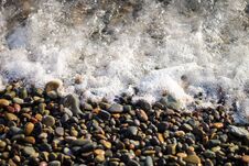 Sea Foam From Small Waves. Crystal Clear Water On The Seashore. The Beach Is Lined With Small Colorful Pebbles. Stock Photography