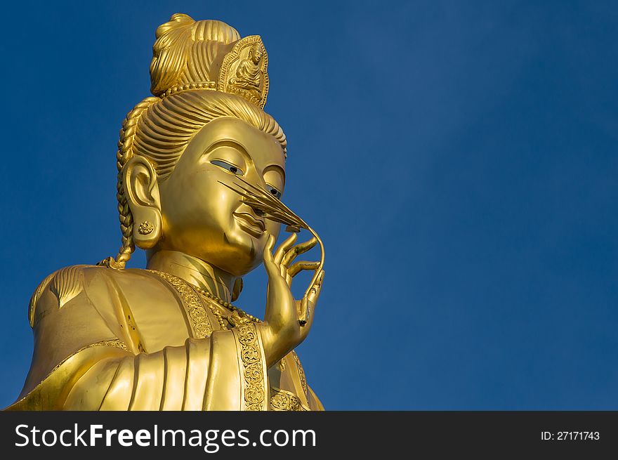 Clos up shot of Golden Guanyin standing with bluesky in Buddhist temple. Clos up shot of Golden Guanyin standing with bluesky in Buddhist temple